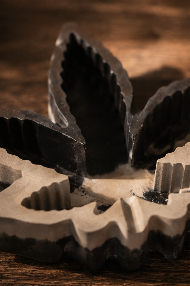 A collage showing a leaf-shaped incense holder and incense sticks in use. The product appears in close-up and in a styled tabletop setting with a hand dipping a incense stick into the holder, on a wooden surface with woven mats and small plants in the background.